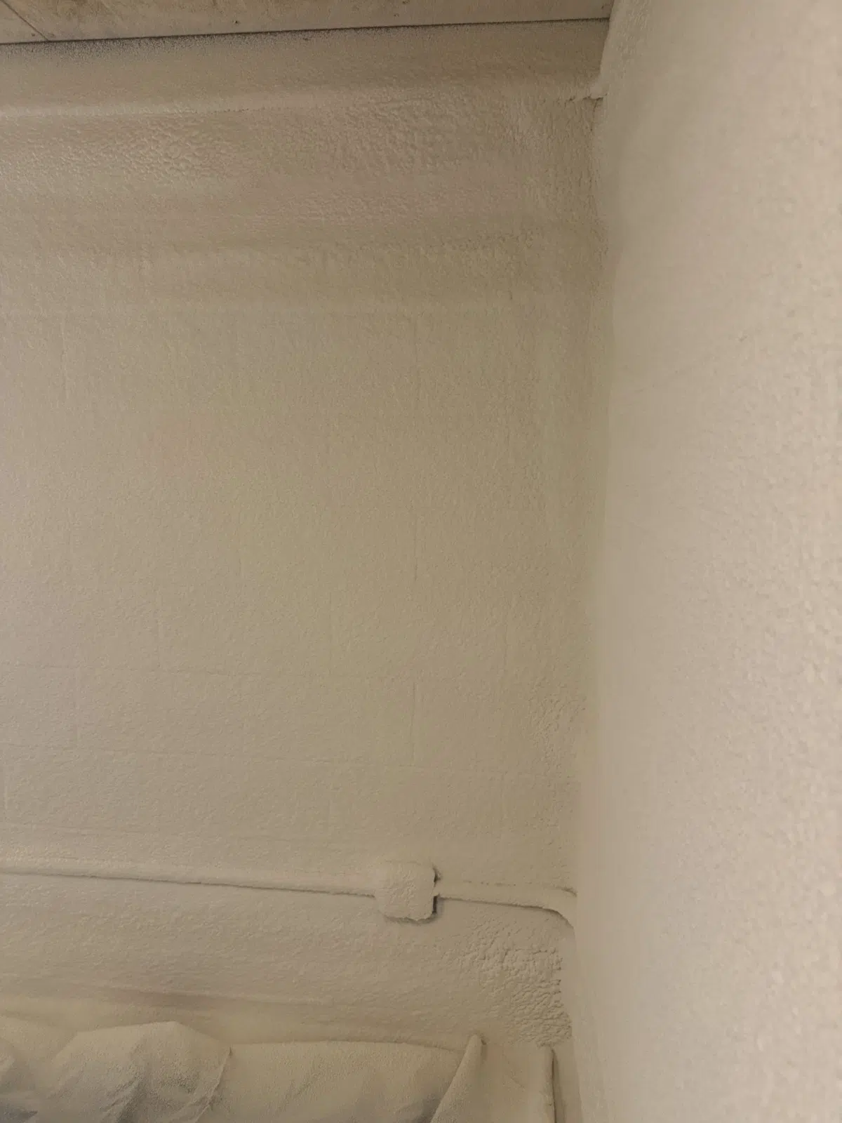 Close-up of white spray foam coating a basement wall corner — Missouri Foam Solutions in Thayer